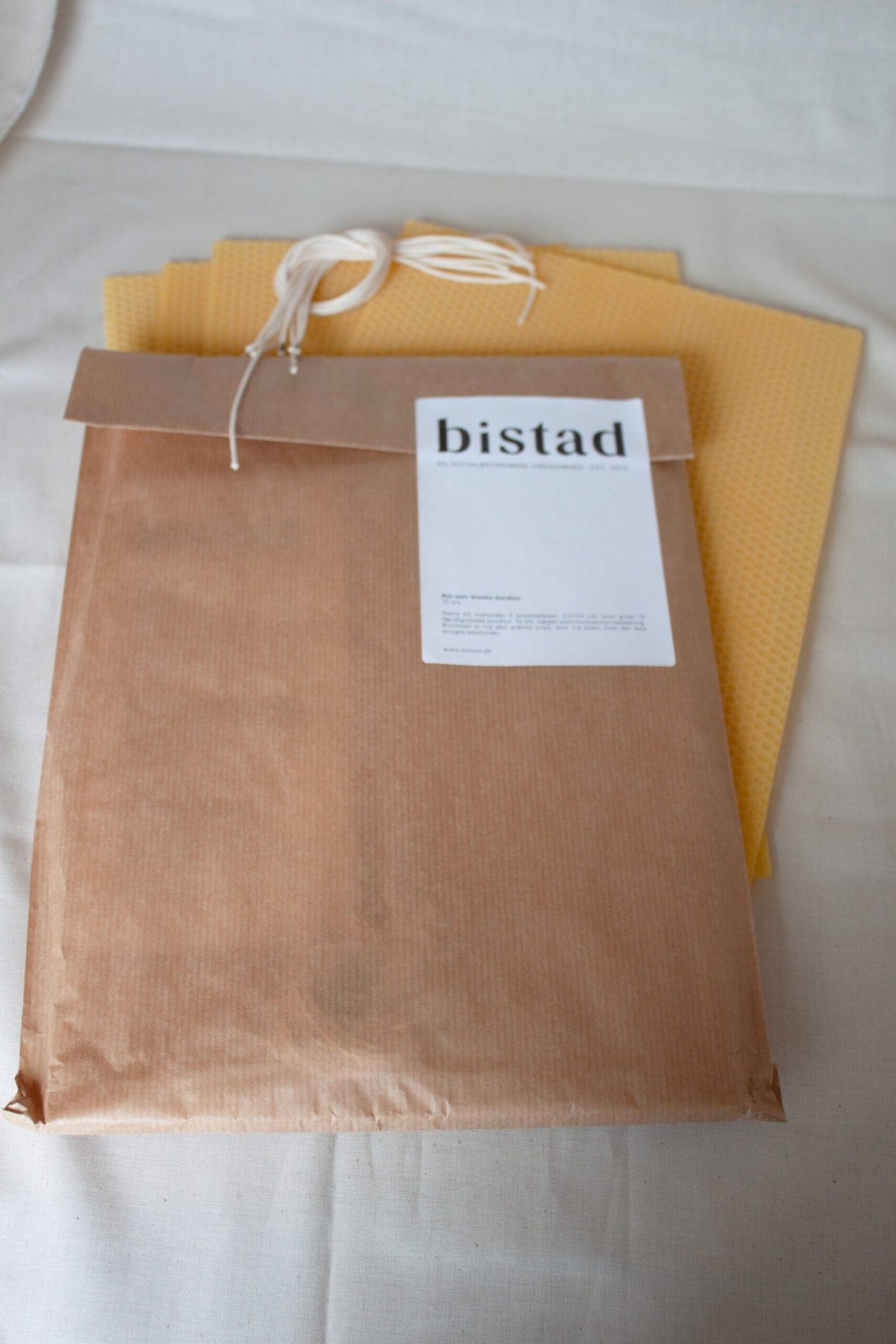 Bistad rull selv bivokslys, bordlys, gule i bivoks, vist i emballasje med voksark som stikker ut