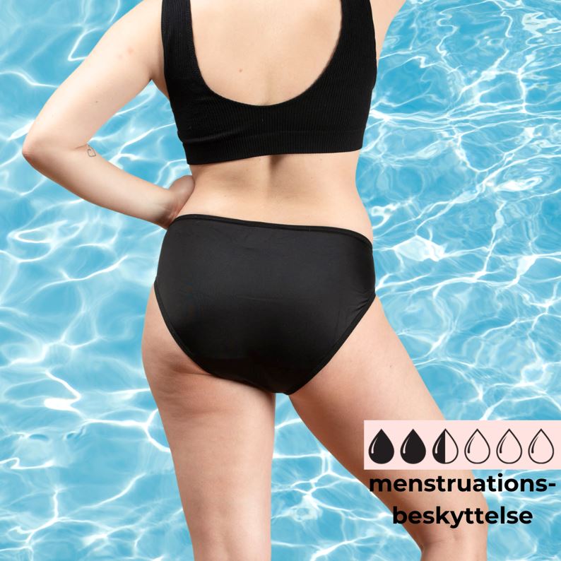 Comfydence Sunshine Bikini menstruse, svart, i stoff, sett bakfra med menstruasjonsbeskyttelses-ikon