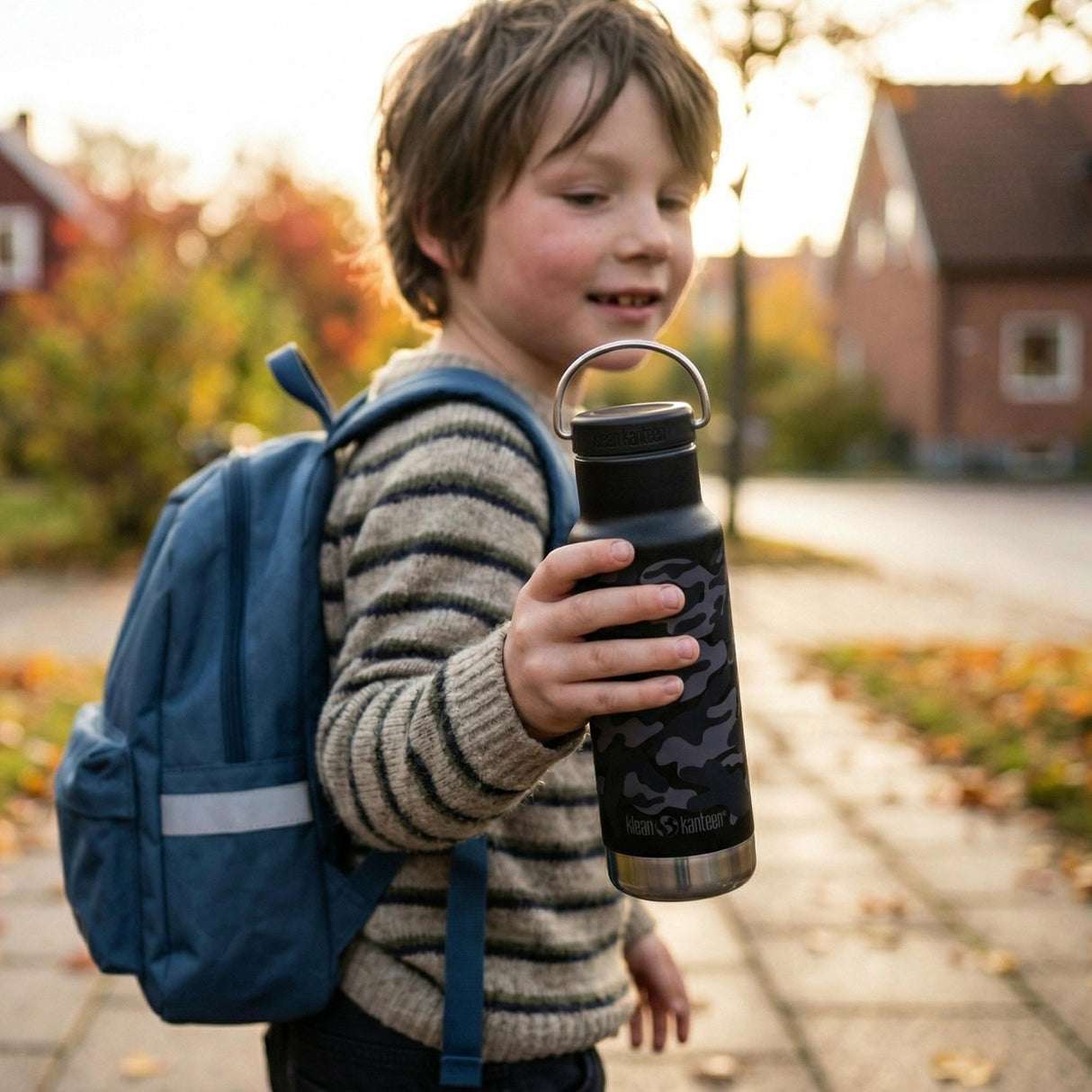 Klean Kanteen isolert termoflaske 355 ml Black Camo i rustfritt stål, holdt av et barn i bruk på fortauet