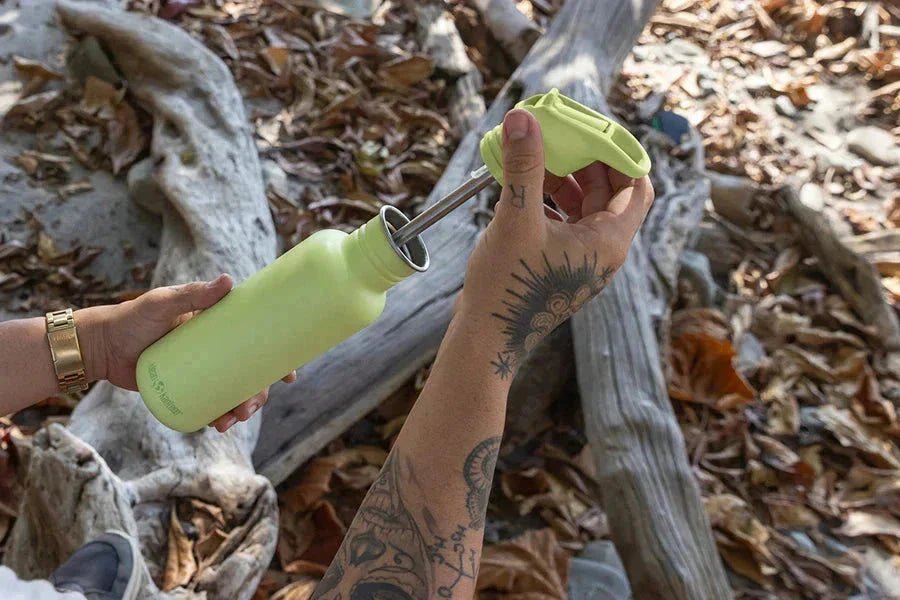 Klean Kanteen Classic drikkeflaske 532ml Sea Spray i rustfritt stål, i bruk med sugerør på en strand