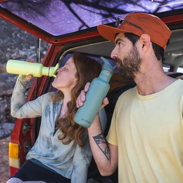 Klean Kanteen Classic drikkeflaske 800ml Clear Sky i rustfritt stål, i bruk av to personer i en bil