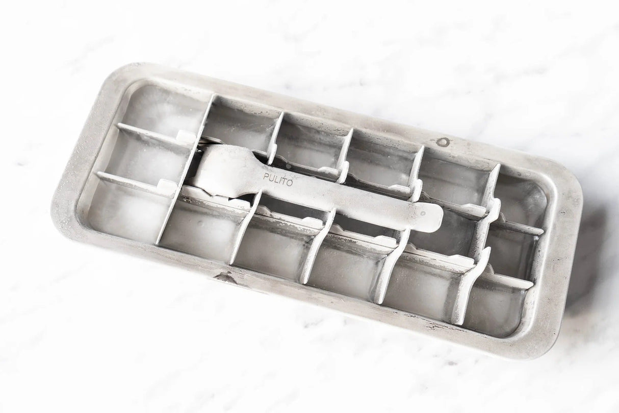 Pulito isbitform i rustfritt stål, fylt med isbiter, sett ovenfra på en hvit marmoroverflate
