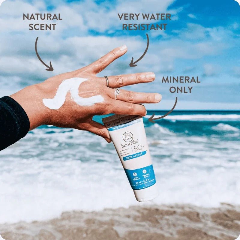 Suntribe Mineral Solkrem SPF 50, 100 ml, beige og blå i tube, holdt i en hånd med krem på håndbaken