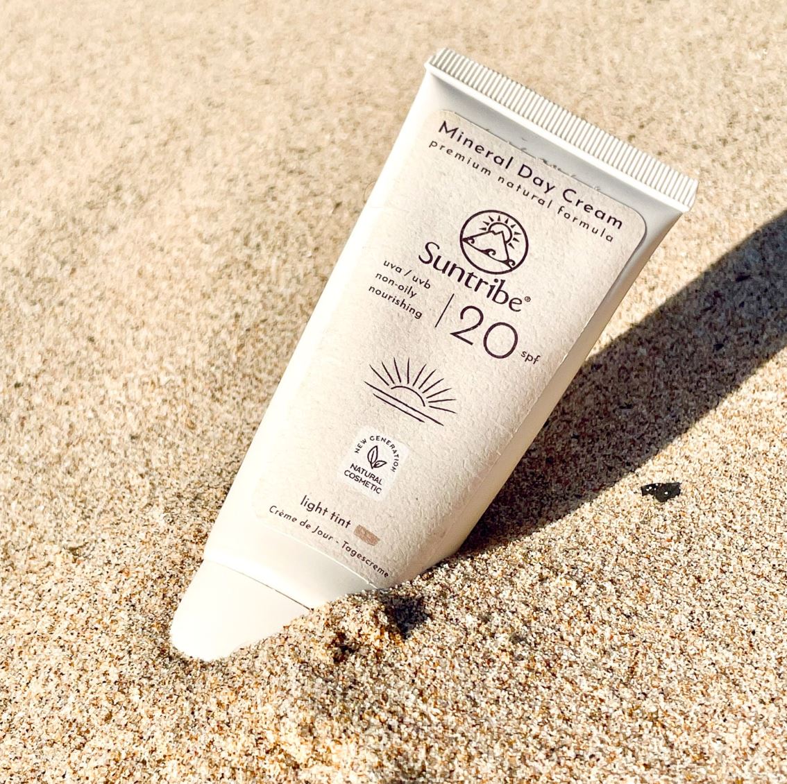 Suntribe Ansiktskrem med solfaktor SPF 20 Tinted 50 ml i plasttube, delvis dekket av sand