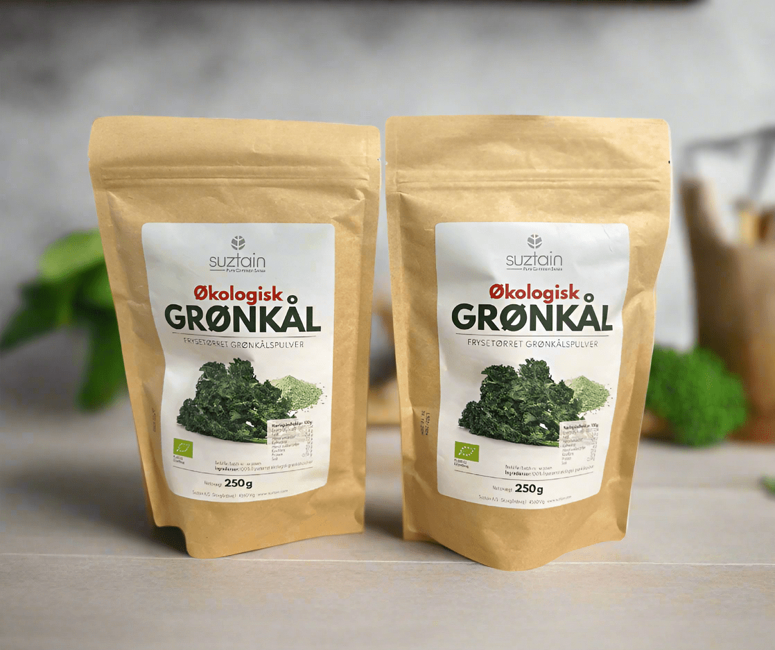 Suztain økologisk frysetørket grønnkålspulver 250g i brun papirpose på kjøkkenbord med grønt i bakgrunnen