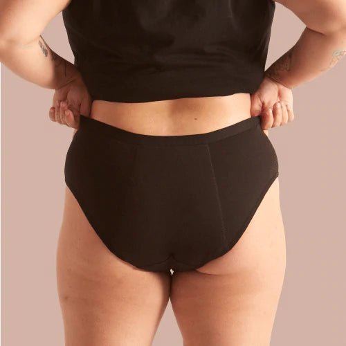 WUKA Basics Hipster Medium Flow i svart bomull, sett bakfra på en modell som holder i linningen