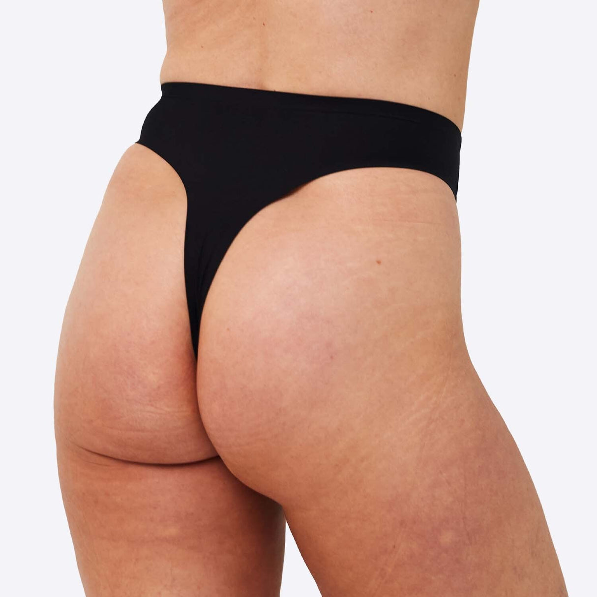 WUKA Stretch Thong Light/Medium flow svart i tekstil, modell iført trusen sett bakfra