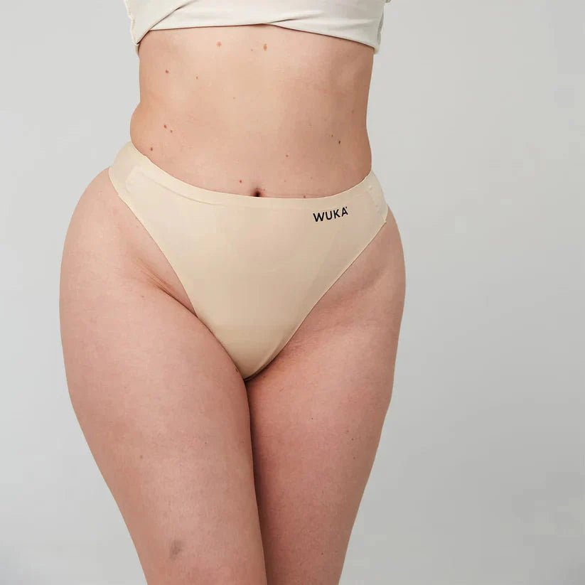 WUKA Stretch Thong for Light-Medium Flow i nude, sett på modell med WUKA logo synlig
