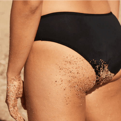 WUKA Swim Bikini Brief Light Flow Svart i stoff, i bruk på en person med sand på hud og truse