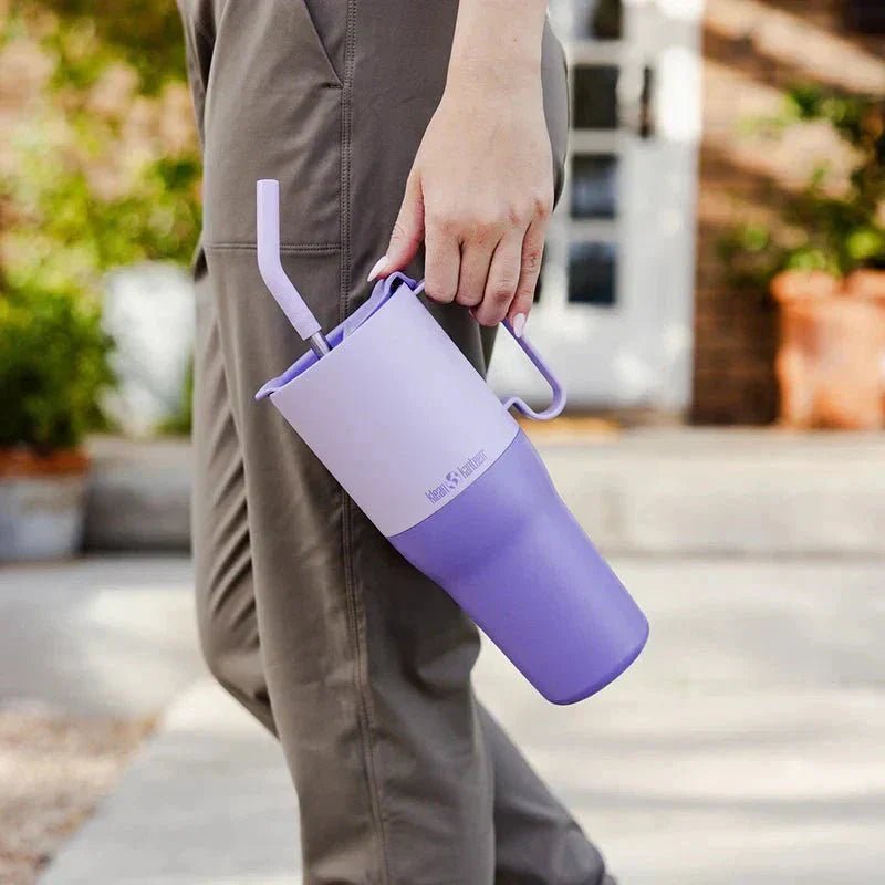 Stor tofarget lilla tumbler på 1005 ml fra Klean Kanteen, holdt i hånden av en person