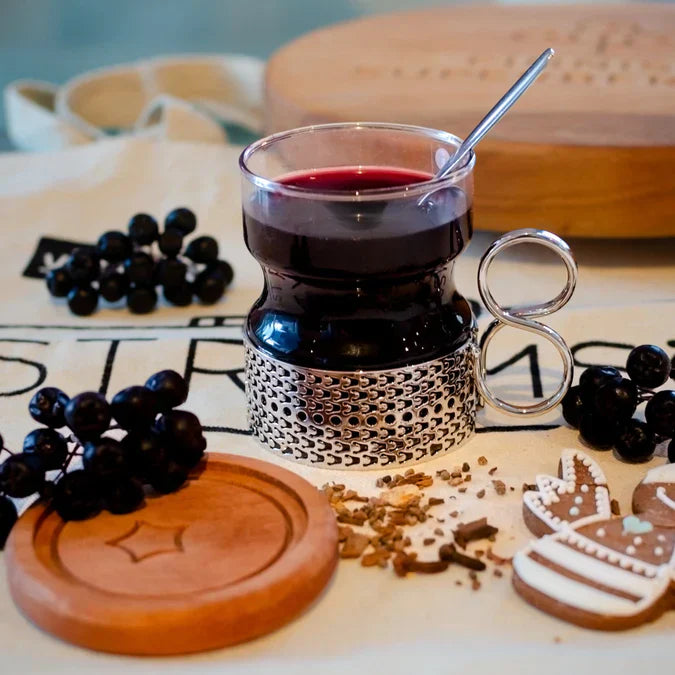 Viser et glass med Aronia saft omgitt av svartsurbær og pepperkake