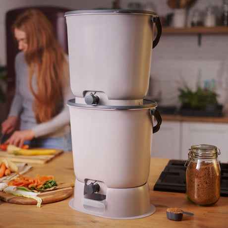 Viser 2 stk Bokashi Essence Kompostbøtter i lys gråfarge, inkl. 1 kg Bokashi-strø - effektiv kompost av kjøkkenavfall.