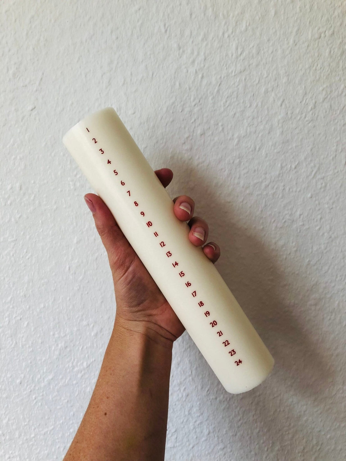 Åbenlys Kalenderlys, kubbelys med røde tall, 25 cm i stearin og soyavoks, holdt i en hånd