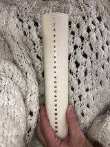 Åbenlys Kalenderlys Kubbelys 25 cm i hvit stearin og soyavoks, holdt i en hånd mot strikket bakgrunn