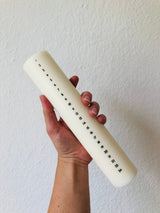 Åbenlys Kalenderlys Kubbelys 25 cm i hvit stearin og soyavoks, holdt i en hånd mot hvit bakgrunn
