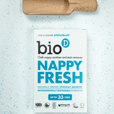 Bio-D Nappy Fresh desinfeksjonspulver 500g på lys bakgrunn med trehåndtak i treverk