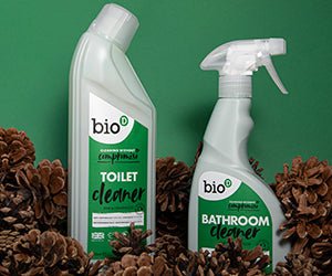 Bio-D Rengjøringsspray til badet 500ml med furu og sedertre omgitt av kongler mot grønn bakgrunn