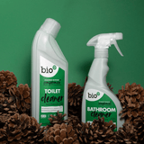 Bio-D toalettrens 750ml i hvit flaske med grønn etikett omgitt av kongler mot grønn bakgrunn