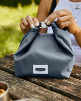 black+blum Matpose 6,7L Skifer i polyester på et trebord, med hender som fester spennen