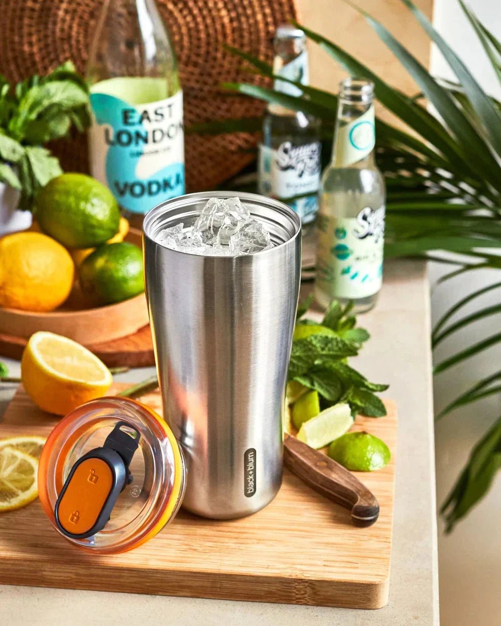 black+blum Termokopp Tumbler Olive i rustfritt stål og plast, fylt med isbiter på et skjærebrett