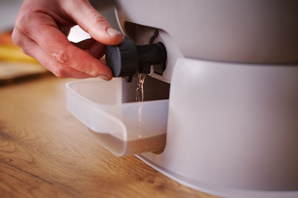Bokashi Essence kompostbøtte i grå plast med tappekran i bruk på kjøkkenbenk