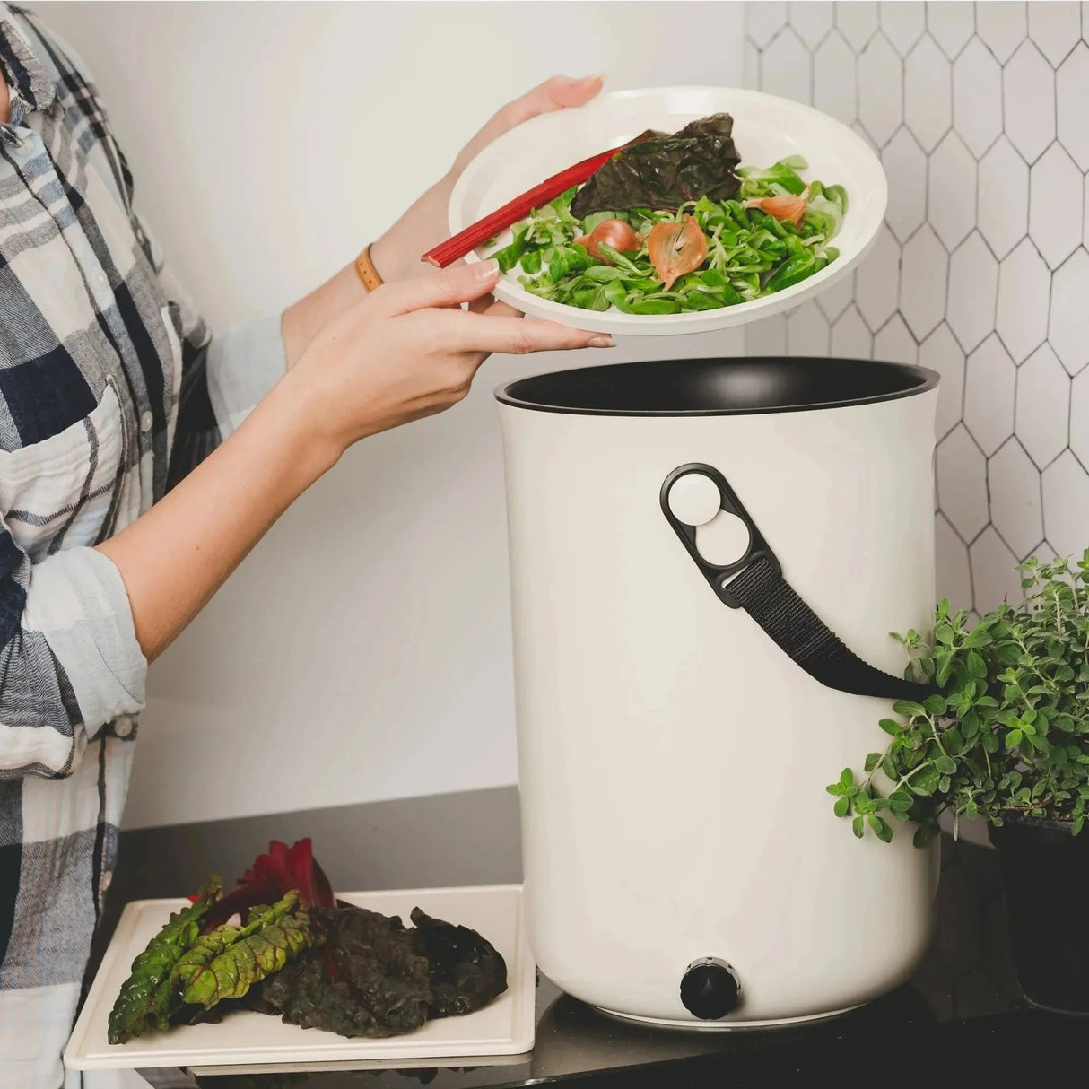 Bokashi Kompostbøtte 2.0 Hvit i plast, en person som tømmer matrester fra en tallerken