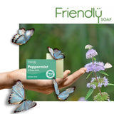 Friendly Soap såpestykke Peppermint & Poppy Seeds (95g) i lys grønn farge, holdt i en hånd med sommerfugler rundt