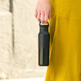 Klean Kanteen Classic Arch Loop Cap i svart polypropylen, en hånd som holder en flaske i bruk