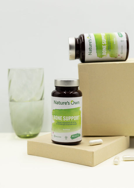 Natures Own Bone Support 60 kapsler i brun flaske med grønn etikett og to hvite kapsler på en eske