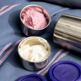 Pulito Pure Dip Box 250 ml hvit og rosa i rustfritt stål, med lilla lokk og en flaske i bakgrunnen