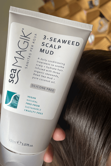 Sea Magik 3 Seaweed Scalp Mud 150ml i hvit plasttube, holdt over en persons mørke hår