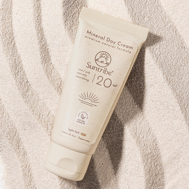 Suntribe Ansiktskrem med solfaktor SPF 20 Tinted 50 ml i plasttube, sett ovenfra på sand Suztain.no