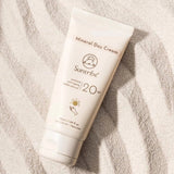 Suntribe Ansiktskrem SPF 20 Untinted 50 ml i hvit tube, liggende på hvit sand med bølgemønster