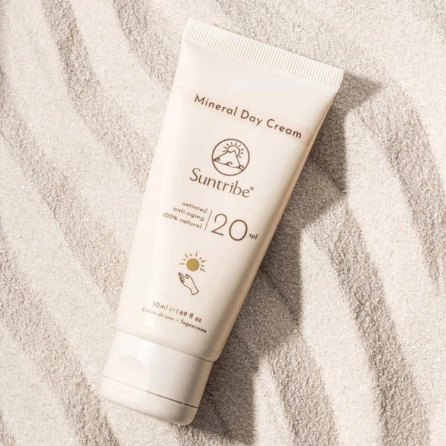 Suntribe Ansiktskrem SPF 20 Untinted 50 ml i hvit tube, liggende på hvit sand med bølgemønster Suztain.no