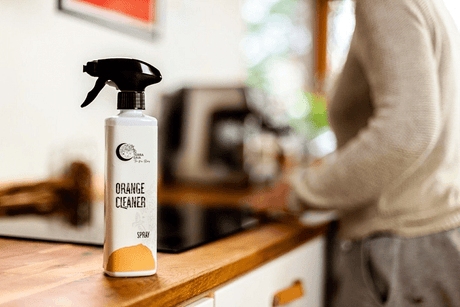 Terra Gaia Rengjøringsspray Økologisk 500ml appelsin på kjøkkenbenk ved siden av person i lys genser