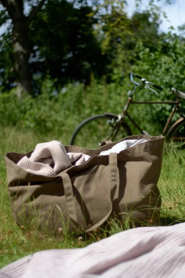 The Organic Company Big Long Bag veske leire i bomull, sett forfra med innhold i gresset