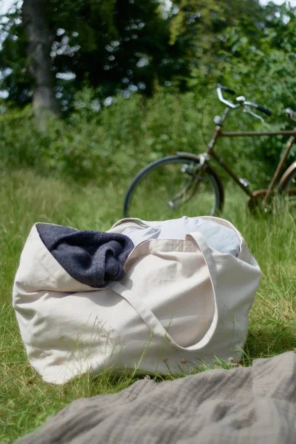 The Organic Company Big Long Bag veske Lys Beige i bomull, i bruk på gress med sykkel i bakgrunnen