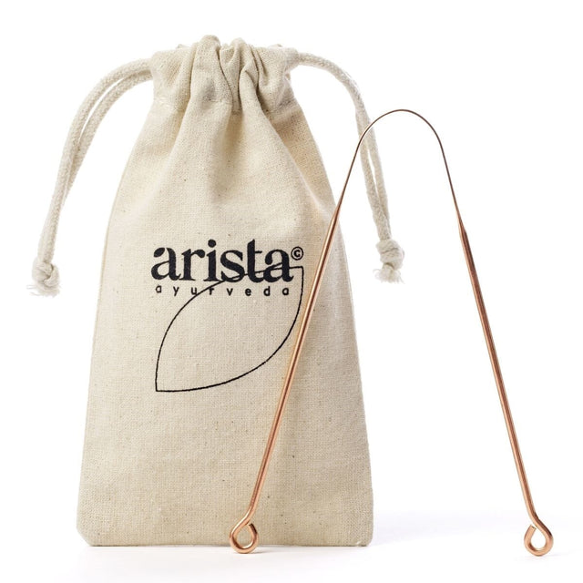 Arista Ayurveda tungeskrape i kobber i kobber i metall, med en tøypose med logo i bakgrunnen Suztain.no