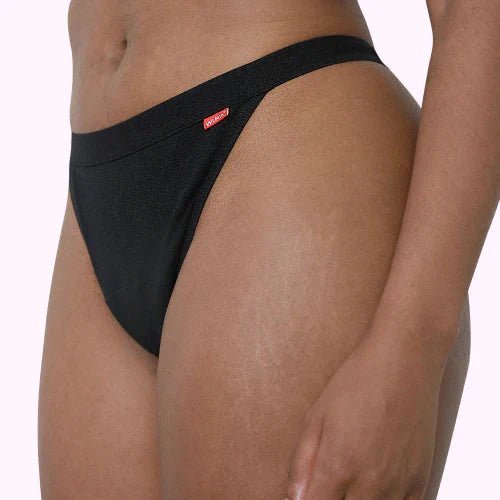 WUKA Basics™ Thong Light Flow i svart bomull på en modell, sett fra siden med fokus på passform