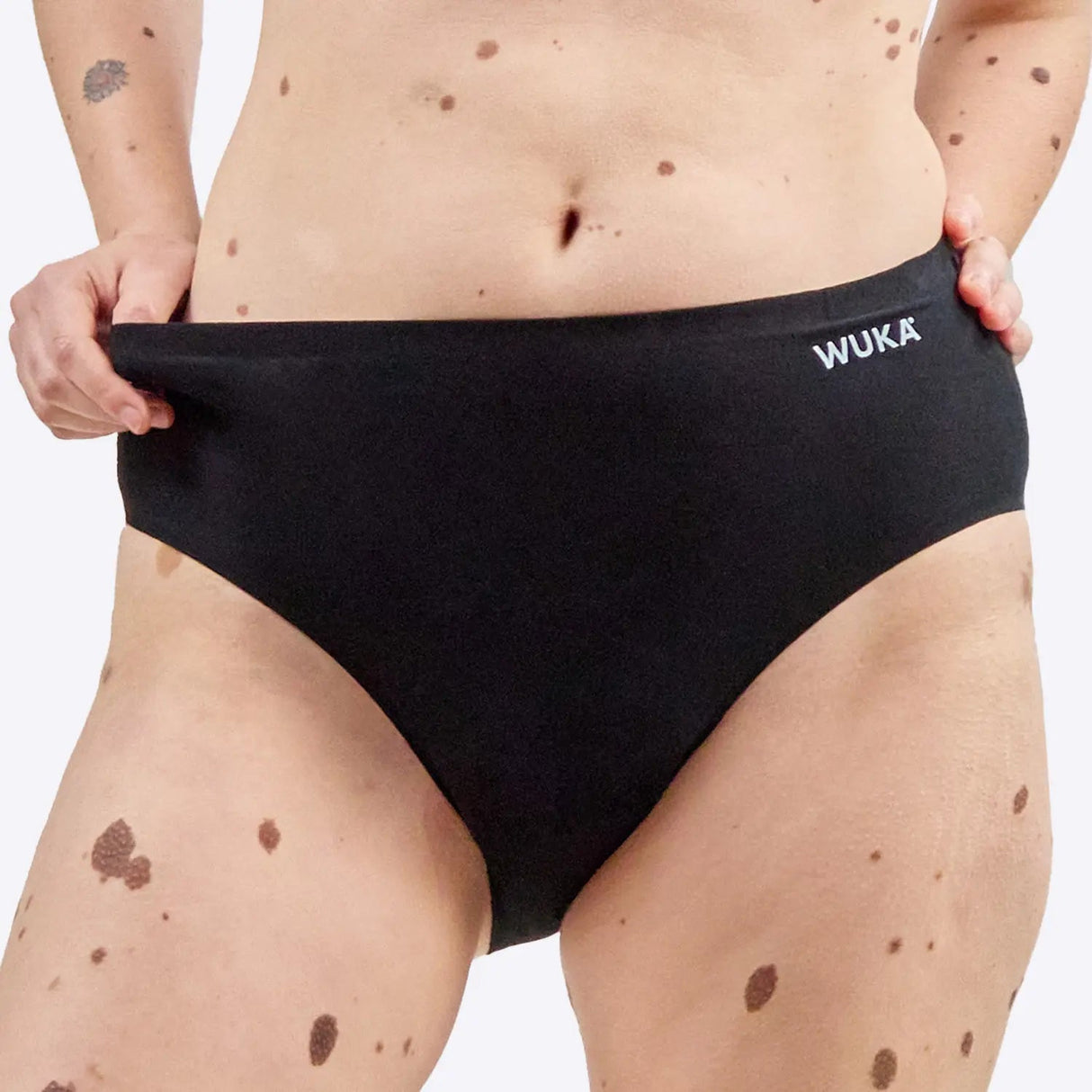 Wuka Stretch Cotton Midi Brief Heavy Flow i svart bomull, en kvinne holder i kanten av trusen