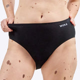 Wuka Stretch Cotton Midi Brief Heavy Flow i svart bomull, en kvinne holder i kanten av trusen