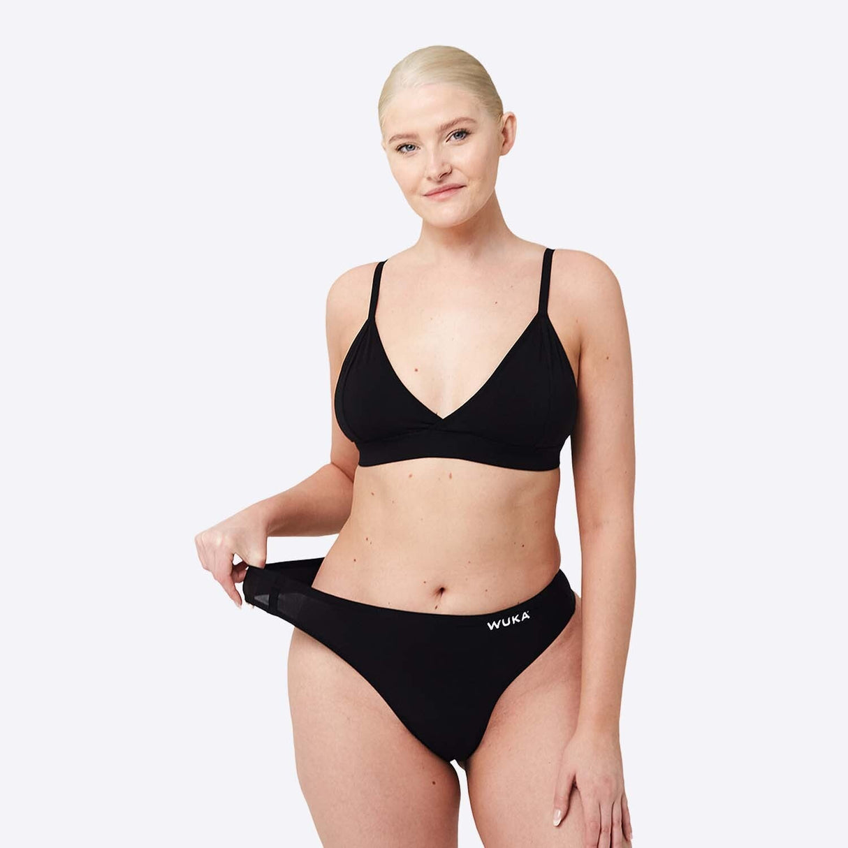 WUKA Stretch Thong Light/Medium flow svart i tekstil, modell strekker ut trusestrikken sett forfra