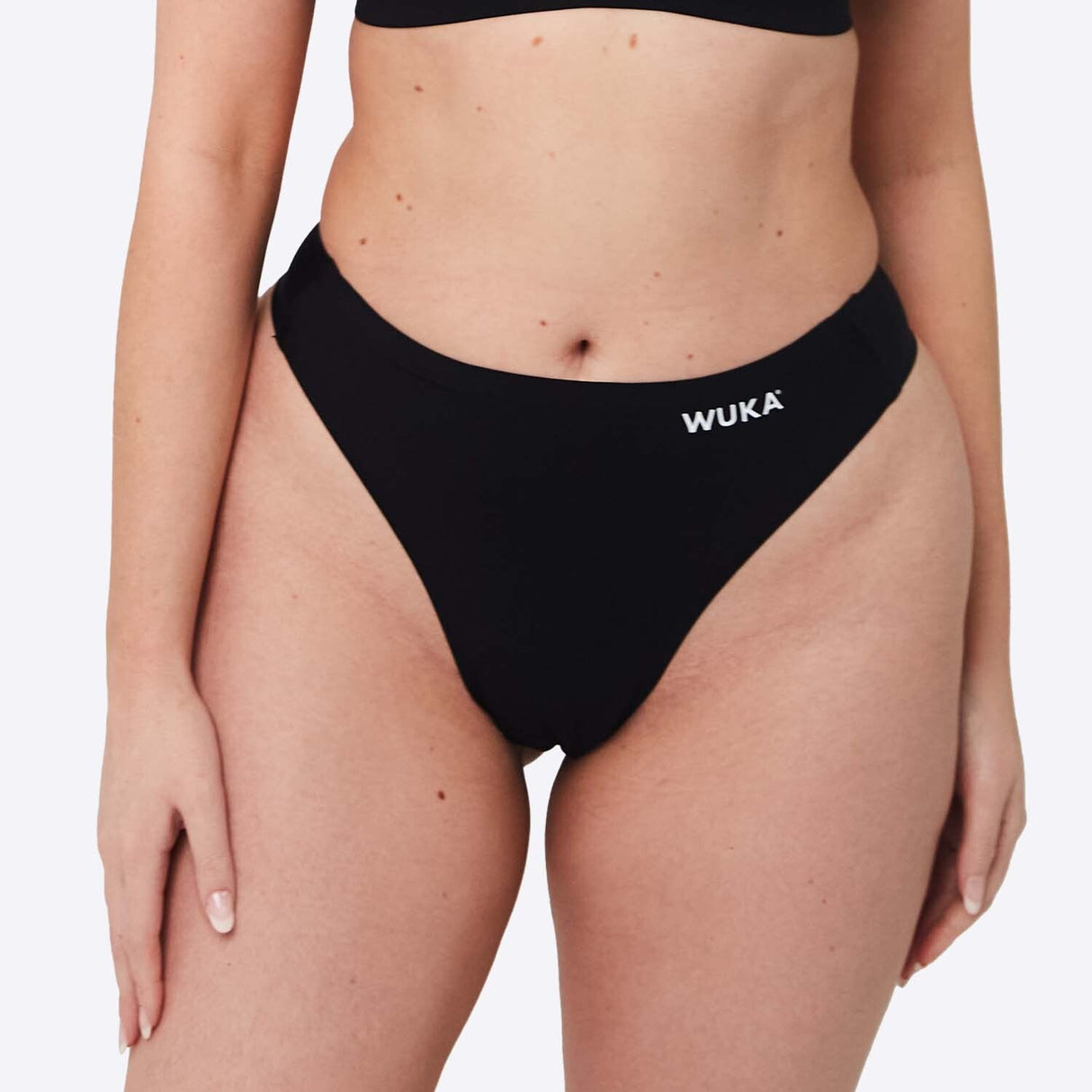 WUKA Stretch Thong Light/Medium flow svart i tekstil, modell iført trusen sett forfra med WUKA-logo