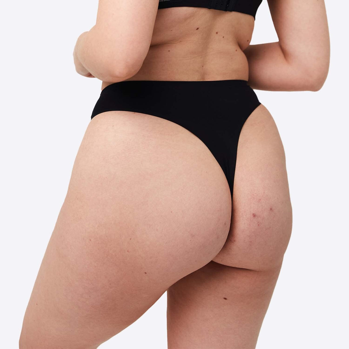 WUKA Stretch Thong Light/Medium flow svart i tekstil, modell iført trusen sett fra skrått forfra