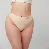 WUKA Stretch Thong for Light-Medium Flow i nude, sett på modell med WUKA logo synlig